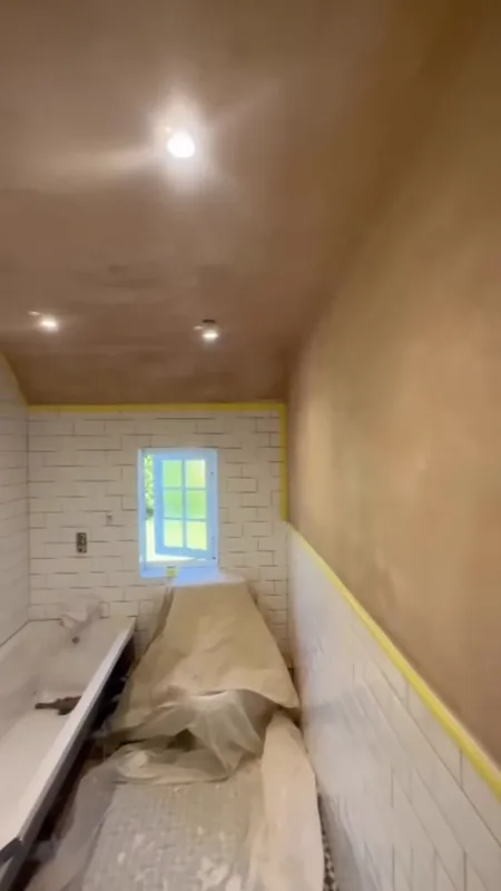 The length of the bathroom: fresh plaster above the new tiles, then painted — before
