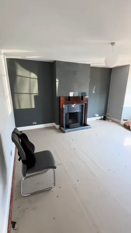 The living room: a dark green chimney breast and fresh walls — before