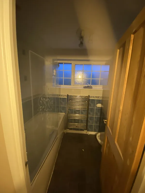 Bathroom: bath replaced with a shower, new tiles, WC and towel rail — before