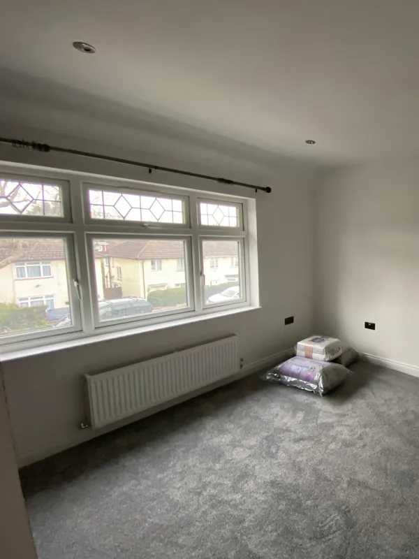 Main front bedroom: same leaded window, now replastered, carpeted and decorated — after