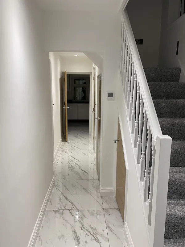 Hallway from the front door: new marble-effect tiles, staircase and doors — after