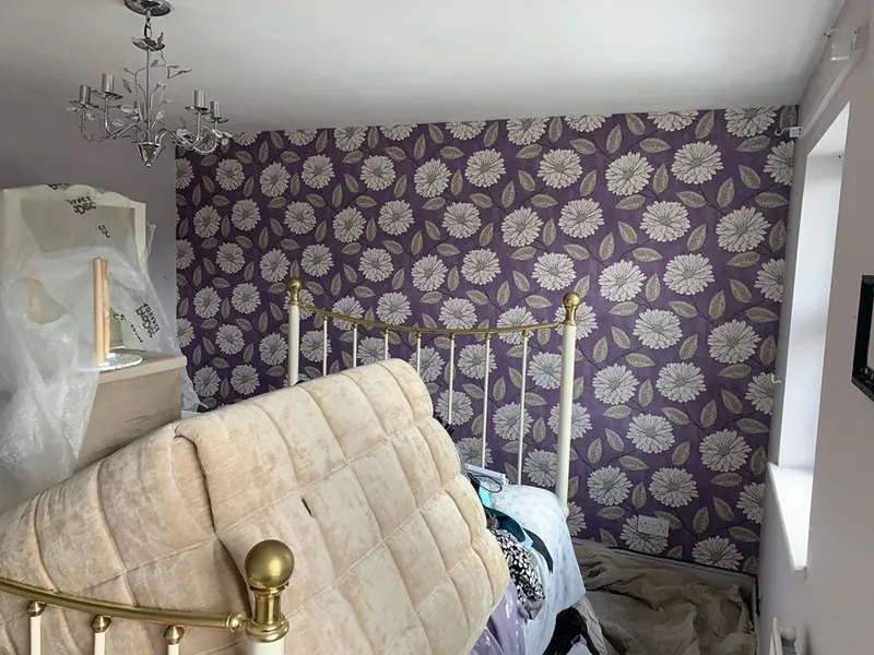 A bedroom: floral wallpaper off, walls painted grey — before